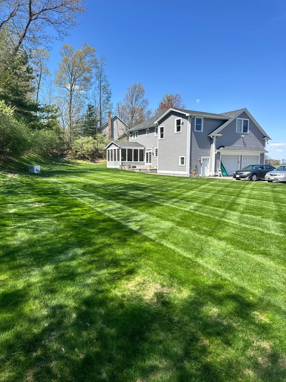 Freshly mowed side yard with straight striping next to a gray house